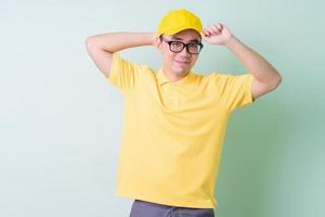 Young Asian delivery man posing on green background photo