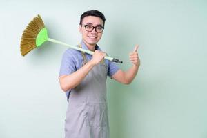 Young Asian man wearing apron posing on green background photo