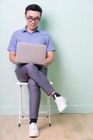 Young Asian buisnessman sitting on chair in green background photo