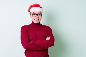 Young Asian man wearing christmas hat on green background photo