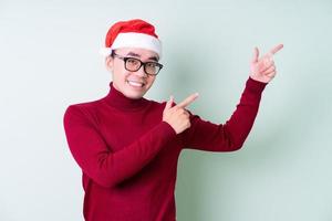 Young Asian man wearing christmas hat on green background photo