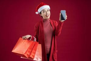 Young Asian woman wearing christmas hat on red background photo