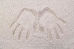 The imprint of two human palms on the sand from above photo