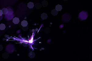 Sparkler in violet and white light on a black background photo