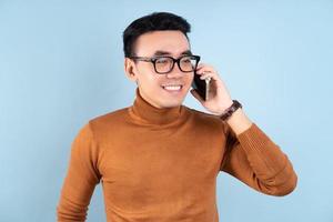 Asian man using smartphone on blue background photo