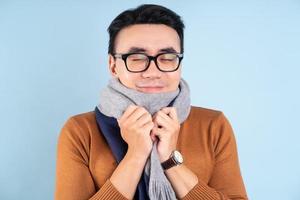 Asian man wearing winter clothes on blue background