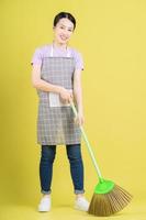 Young Asian housewife posing on yellow background photo