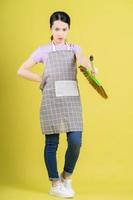 Young Asian housewife posing on yellow background photo