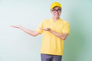 Young Asian delivery man posing on green background photo