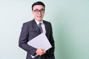 joven empresario asiático posando sobre fondo verde foto