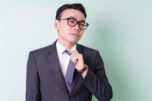 Young Asian businessman posing on green background photo