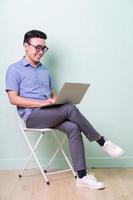 Young Asian buisnessman sitting on chair in green background photo