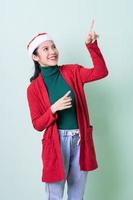 Young Asian woman wearing christmas hat on green background, x-mas concept photo