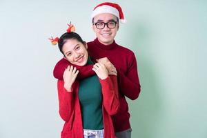 Joven pareja asiática posando sobre fondo verde con concepto de Navidad foto