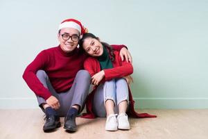 Young Asian couple posing on green background with christmas concept photo