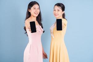 Two young Asian women wearing dress on blue background photo