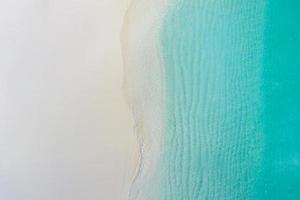 Summer seascape beautiful waves, blue sea water in sunny day. Top view from drone. Sea aerial view, amazing tropical nature background. Beautiful bright sea with waves splashing and beach sand concept photo