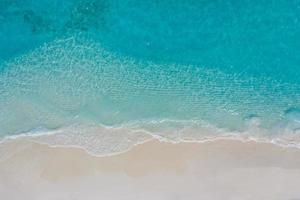 Summer seascape beautiful waves, blue sea water in sunny day. Top view from drone. Sea aerial view, amazing tropical nature background. Beautiful bright sea with waves splashing and beach sand concept photo