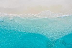 Summer seascape beautiful waves, blue sea water in sunny day. Top view from drone. Sea aerial view, amazing tropical nature background. Beautiful bright sea with waves splashing and beach sand concept photo