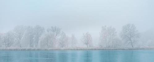 niebla de la mañana panorámica sobre el lago congelado. paisaje de la naturaleza de invierno. brumoso sol de la mañana brumosa, sereno escenario natural, helada, frío día de invierno foto