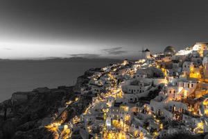 Selective color image, orange color with black and white process. Night lights over Oia village in Santorini, Greece. Famous travel destination, artistic fine art template. Relax, inspire cityscape