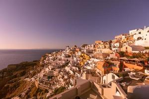 Gorgeous sunset Island Of Santorini Greece, beautiful whitewashed village Oia with church windmill during sunset, streets lights, romantic summer vacation, famous honeymoon couple travel destination