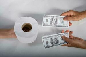Close up sell buy tissue, hand holds toilet paper tissue and money of 100 US dollars banknote a lot of, That was It costs expensive price and high priced products concep photo