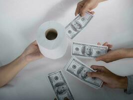 Close up sell buy tissue, hand holds toilet paper tissue and money of 100 US dollars banknote a lot of, That was It costs expensive price and high priced products concep photo