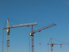 Yellow construction cranes against cloudy sky background. photo