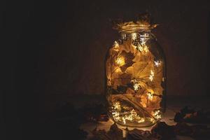 A lamp made from a jar, garland and dried leaves. photo