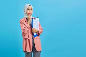 Joven mujer asiática concentrándose en la estrategia de planificación sobre fondo azul. foto