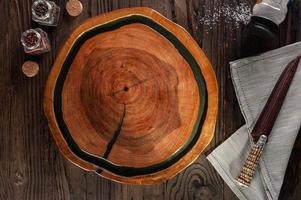 A beautiful wooden carved plate with parrilla salt, spices and knife. photo