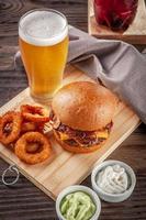 deliciosa hamburguesa de tocino con aros de cebolla y cerveza. foto