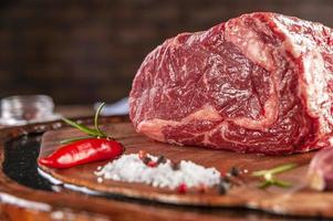 Raw entrecote beef on a wood cutting board with spices - Closeup. photo