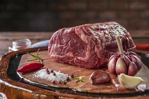 Raw entrecote beef on a wood cutting board with spices on bricks wall background - Closeup. photo