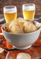 Potato chips in a bowl with two glasses of beer