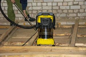 Construction vacuum cleaner. A man clean the surface from dust and debris with a powerful vacuum cleaner at a construction site. photo