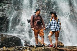 Man and woman hikers trekking a rocky path against background of a waterfall and rocks photo