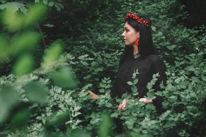 Beautiful girl in black dress and red decorations the background of the forest. Space for your text message or promotional content photo