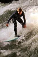 MUNICH, GERMANY, OCTOBER 23 - Unidentified surfer in the Eisbach river in English Garden in Munich, Germany at October 23, 2011. The first surfers discovered the Eisbach in the 1970's. photo