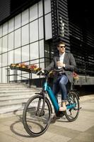 joven empresario en la bicicleta eléctrica con taza de café para llevar foto