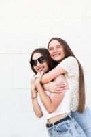 Two female friends hugging outside in a summer day having fun photo