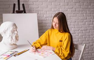 Artista femenina pintando un cuadro con acuarela en el estudio. foto
