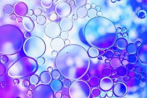 Burbujas de aceite azul y púrpura en el agua con patrón abstracto foto