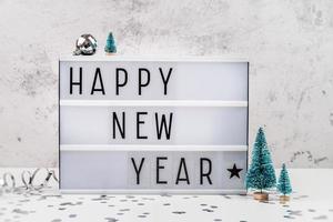 white letter lightbox with Happy New Year surrouded with christmas decorations front view photo