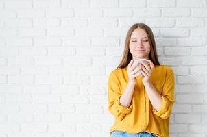 Atractiva mujer adolescente en camisa amarilla bebiendo té foto