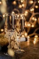 two champagne flute with shiny bottle on dark background with lights photo