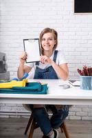 Young blond woman tailor showing a sketch ready to sew a pillow photo