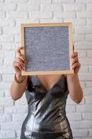 Hermosa mujer en un vestido de fiesta sosteniendo un tablero de letras de fieltro vacío foto