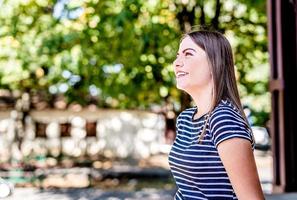 Close up portrait of a beautiful young caucasian woman smiling and looking up outdoors in a sunny day photo